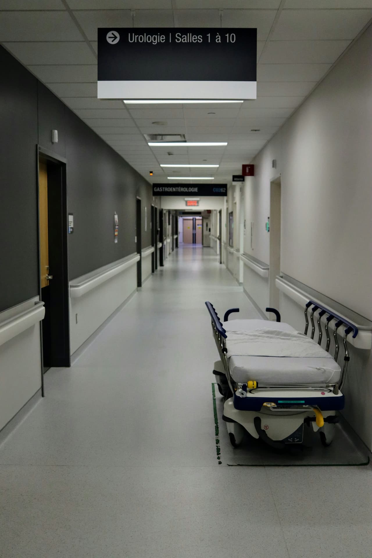 An empty hospital corridor with a gurney parked against the wall